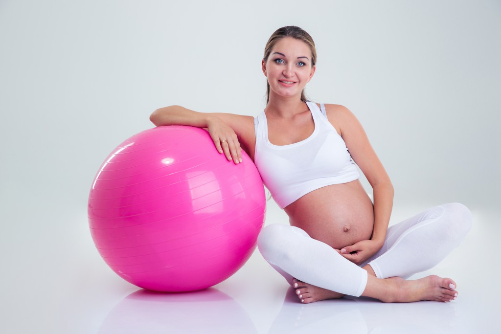 Portrait of a smiling pregnant woman sitting on the floor with f